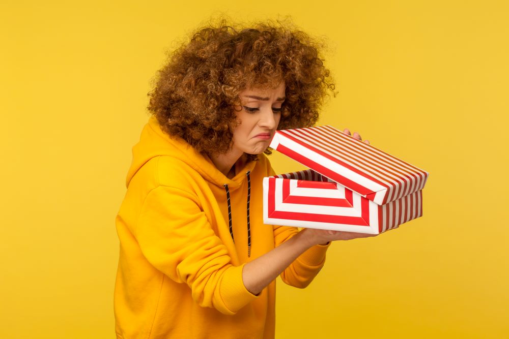 mujer decepcionada mirando en caja de regalo