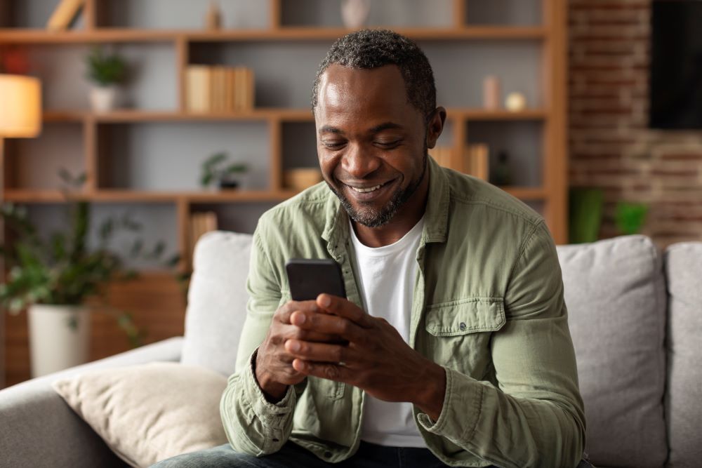 new device app portrait smiling middle aged african american man reads message phone watches video